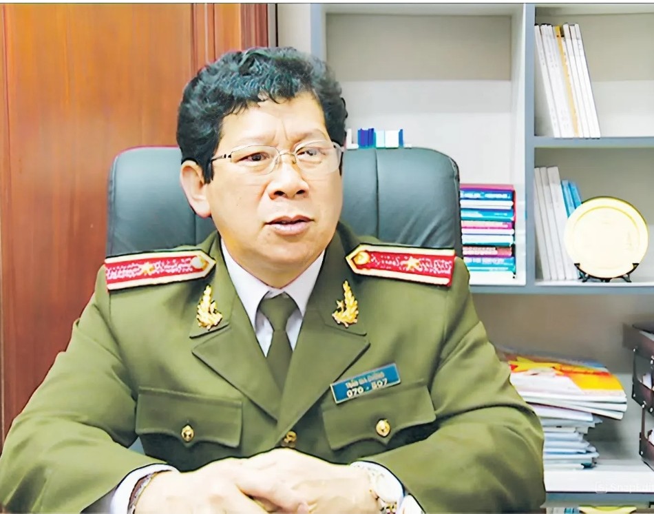 Screenshot20260419181629086com android chrome catrawarta Male military officer in a green dress uniform with red shoulder boards seated at a desk in an office hands resting on the table shelves and files in the background